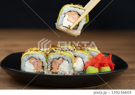 delicious traditional Japanese sushi and rolls on a plate holding chopsticks delicious traditional Japanese sushi and rolls on a plate holding chopsticks 139236605