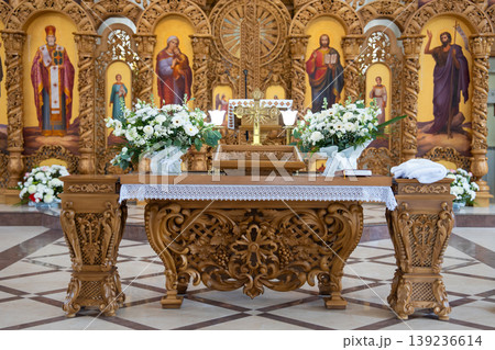 Ornate wooden altar with floral arrangements and iconostasis background Ornate wooden altar with floral arrangements and iconostasis background 139236614