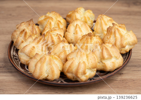 Plate of golden star-shaped profiteroles on a wooden table Plate of golden star-shaped profiteroles on a wooden table 139236625