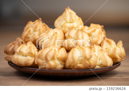 Plate of golden star-shaped profiteroles on a wooden table 139236626
