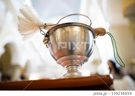 Low-angle shot of a holy water bowl and aspergillum in a church Low-angle shot of a holy water bowl and aspergillum in a church 139236859