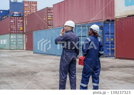 Diverse Mid-adult Caucasian Male and Black Female Logistics Workers Using Radio at a Cargo Shipping Terminal Diverse Mid-adult Caucasian Male and Black Female Logistics Workers Using Radio at a Cargo Shipping Terminal 139237323