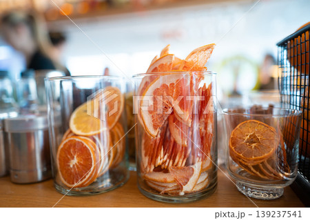 Dried citrus slices in glass jars on a bar counter 139237541