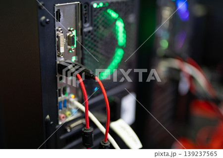 Rear panel of a PC case with connected cables and green LED fan 139237565