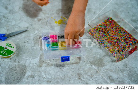 A creative girl is engaged in beadwork. Hobby and small business concept A creative girl is engaged in beadwork. Hobby and small business concept 139237732