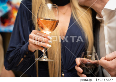 Woman holding a glass of rose wine at a social gathering Woman holding a glass of rose wine at a social gathering 139237827