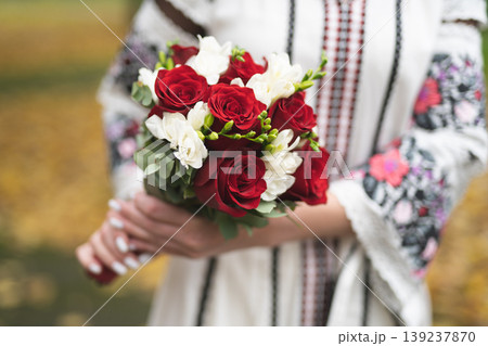 the bride and groom are holding hands with a bouquet of flowers and in traditional Ukrainian clothes 139237870