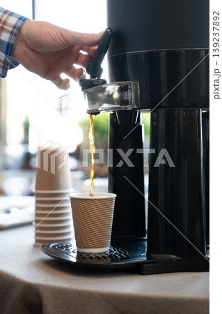 Fresh hot coffee being poured from a commercial dispenser into a paper cup Fresh hot coffee being poured from a commercial dispenser into a paper cup 139237892