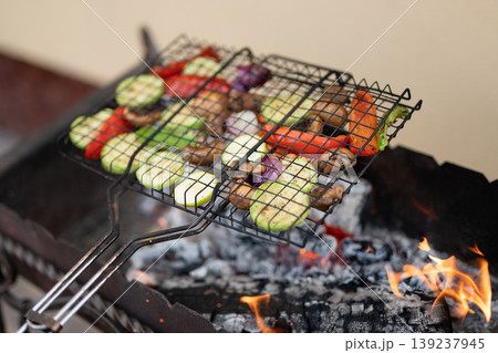 Sliced vegetables grilling on a wire rack over an open fire Sliced vegetables grilling on a wire rack over an open fire 139237945
