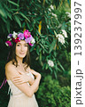 Close up portrait of a beautiful young girl with flower wreath in a sunny garden 139237997