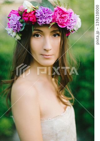 Close up portrait of a beautiful young girl with flower wreath in a sunny garden Close up portrait of a beautiful young girl with flower wreath in a sunny garden 139238000