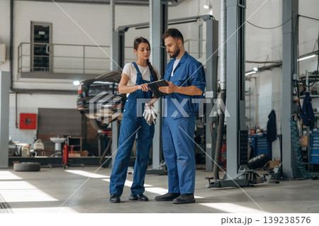 Data is in the digital tablet. Auto repair shop employees are working together. Man and woman 139238576