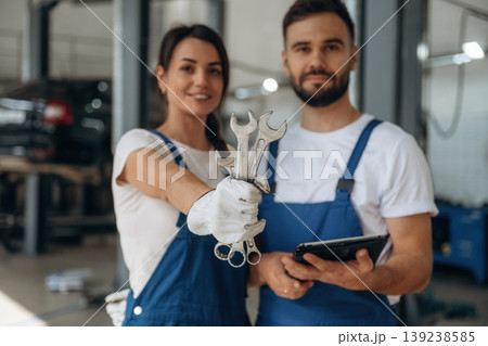 Showing the tools. Auto repair shop employees are working together. Man and woman Showing the tools. Auto repair shop employees are working together. Man and woman 139238585