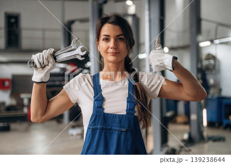 Posing, showing wrenches. Female mechanic is working in the modern car workshop Posing, showing wrenches. Female mechanic is working in the modern car workshop 139238644