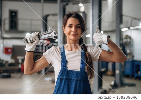 Posing, showing wrenches. Female mechanic is working in the modern car workshop Posing, showing wrenches. Female mechanic is working in the modern car workshop 139238646