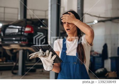 In shock, something went wrong, with digital tablet. Female mechanic is working in the modern car workshop 139238649