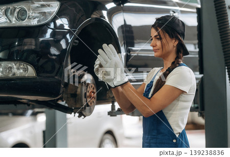 White gloves, wearing them. Female mechanic is working in the modern car workshop White gloves, wearing them. Female mechanic is working in the modern car workshop 139238836