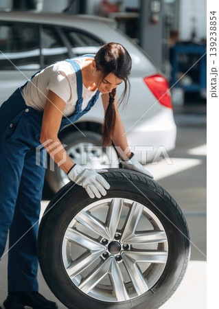 Quality product, moving it. Woman mechanic is with tire in the modern car workshop Quality product, moving it. Woman mechanic is with tire in the modern car workshop 139238854