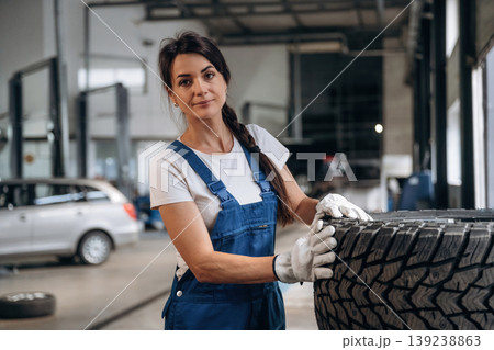 Taking a look at the tire. Female mechanic is working in the modern car workshop 139238863