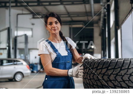 Taking a look at the tire. Female mechanic is working in the modern car workshop 139238865