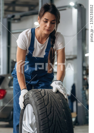 Rolling the wheel. Woman mechanic is with tire in the modern car workshop Rolling the wheel. Woman mechanic is with tire in the modern car workshop 139238882