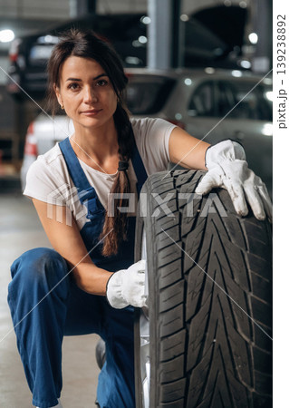 Seasonal replacement conception. Woman mechanic is with tire in the modern car workshop Seasonal replacement conception. Woman mechanic is with tire in the modern car workshop 139238892
