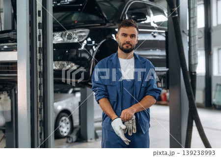Protective gloves in hands. Male mechanic is working in the modern car workshop 139238993