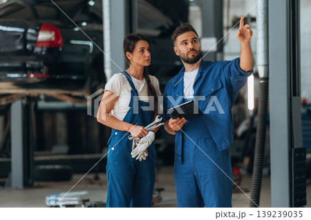 Digital tablet is in hands. Auto repair shop employees are working together. Man and woman Digital tablet is in hands. Auto repair shop employees are working together. Man and woman 139239035