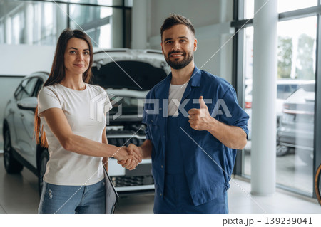 Deal, doing handshake. Woman customer is in the car repair service station with mechanic 139239041