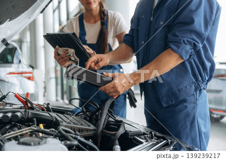 Particle close up view of male and female mechanics that are repairing the car Particle close up view of male and female mechanics that are repairing the car 139239217