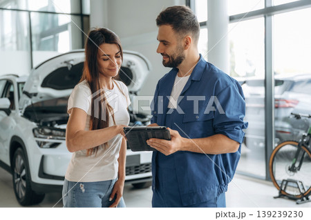 Giving the consultation. Woman customer is in the car repair service station with mechanic Giving the consultation. Woman customer is in the car repair service station with mechanic 139239230