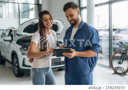 Woman customer is in the car repair service station with mechanic Woman customer is in the car repair service station with mechanic 139239233