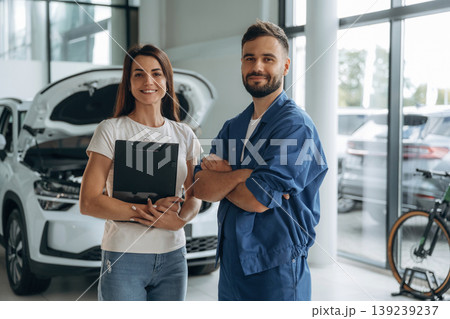 Woman customer is in the car repair service station with mechanic Woman customer is in the car repair service station with mechanic 139239237
