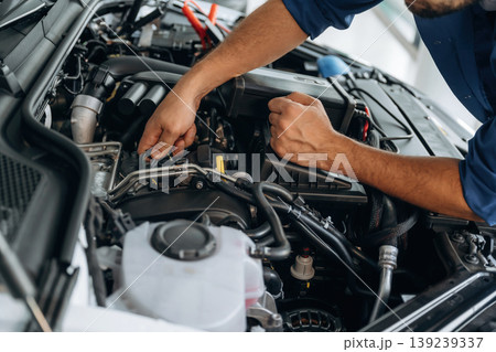Hands visible only, hood is opened, fixing. Close up view of male service station worker at job Hands visible only, hood is opened, fixing. Close up view of male service station worker at job 139239337