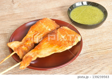 grilled salmon dressing teriyaki sauce stabbing wooden stick on plate dipping spicy chili sauce 139239563