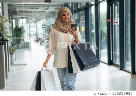 Right after the shopping. Woman in traditional Muslim clothing is indoors in the business building Right after the shopping. Woman in traditional Muslim clothing is indoors in the business building 139239959