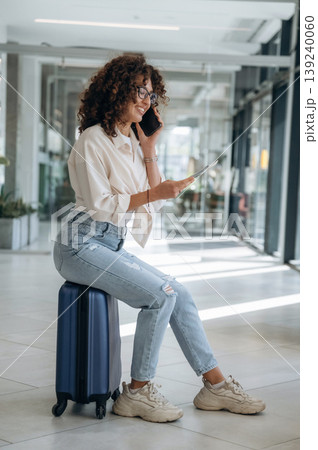 Holding the ticket. Beautiful woman is in airport hall with suitcase Holding the ticket. Beautiful woman is in airport hall with suitcase 139240060