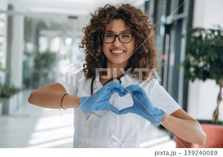 Heart, love gesture by hands. Woman doctor is standing indoors in the clinic Heart, love gesture by hands. Woman doctor is standing indoors in the clinic 139240089