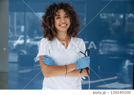 Stethoscope is in hands. Woman doctor is standing indoors in the clinic 139240100
