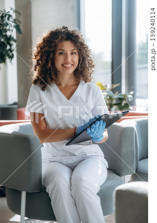 Appointment conception, sitting and ready to listen to you. Woman doctor is standing indoors in the clinic Appointment conception, sitting and ready to listen to you. Woman doctor is standing indoors in the clinic 139240114
