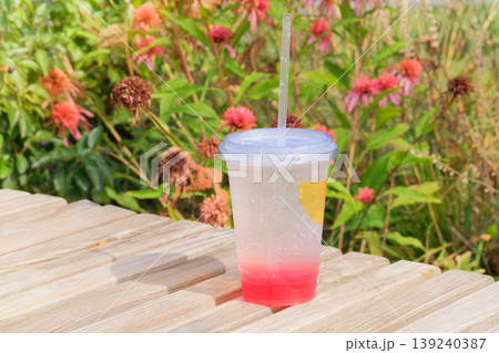 Still life. Refreshment drink in glass with straw on table in park. Cold lemonade in sunny day. Still life. Refreshment drink in glass with straw on table in park. Cold lemonade in sunny day. 139240387