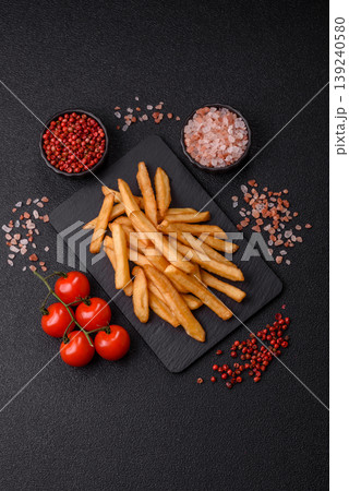 French fries, a salty, crispy, homemade snack with spices. French fries on a black background French fries, a salty, crispy, homemade snack with spices. French fries on a black background 139240580