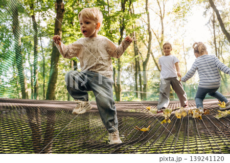 Jumping, active time spending. Kids are playing on the children's amusement ropes course Jumping, active time spending. Kids are playing on the children's amusement ropes course 139241120