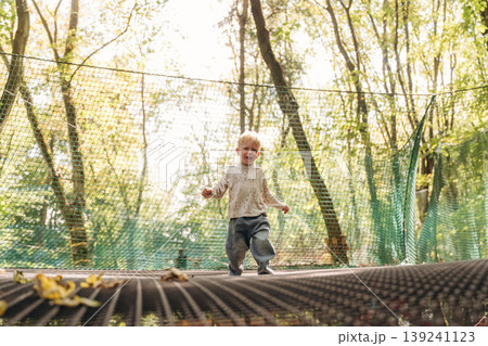 Little boy is playing on the children's amusement ropes course Little boy is playing on the children's amusement ropes course 139241123