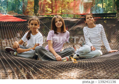 Looking forward, sitting, relaxed. Kids are playing on the children's amusement ropes course Looking forward, sitting, relaxed. Kids are playing on the children's amusement ropes course 139241136