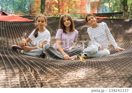 Looking forward, sitting, relaxed. Kids are playing on the children's amusement ropes course 139241137