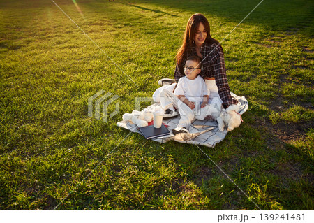 On the picnic blanket. Mother and son together in an open field during daytime On the picnic blanket. Mother and son together in an open field during daytime 139241481