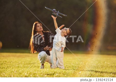 Imagination conception, playing with toy plane. Mother and son together in an open field during daytime 139241514