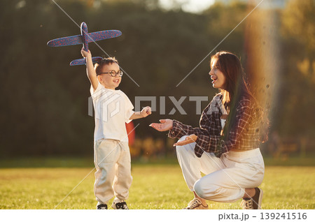 Imagination conception, playing with toy plane. Mother and son together in an open field during daytime 139241516