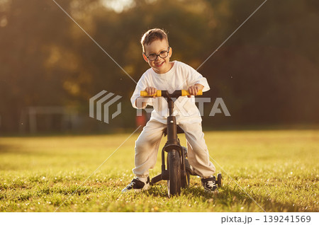 On the small bicycle. Boy is having fun on the field under sunlight at daytime On the small bicycle. Boy is having fun on the field under sunlight at daytime 139241569